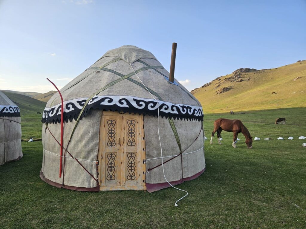 Традиционна киргизка юрта с пасящ кон в зелените пасища на Киргизстан